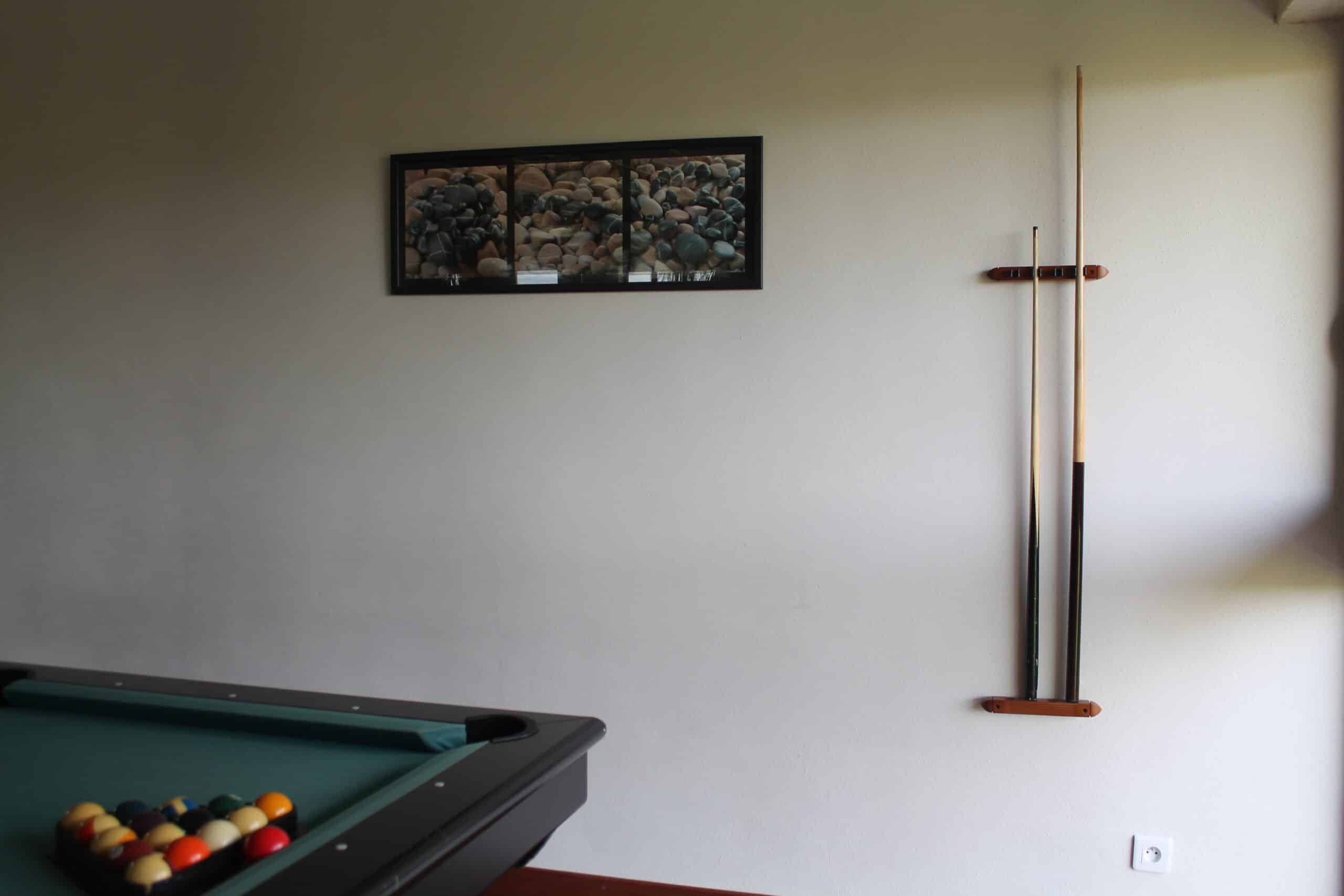 Table de billard avec triangle de boules, queues de billard sur rack mural et cadre photo de galets.